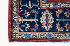 A close-up of a handmade Afghan Chobi rug featuring a blue field with intricate floral patterns.