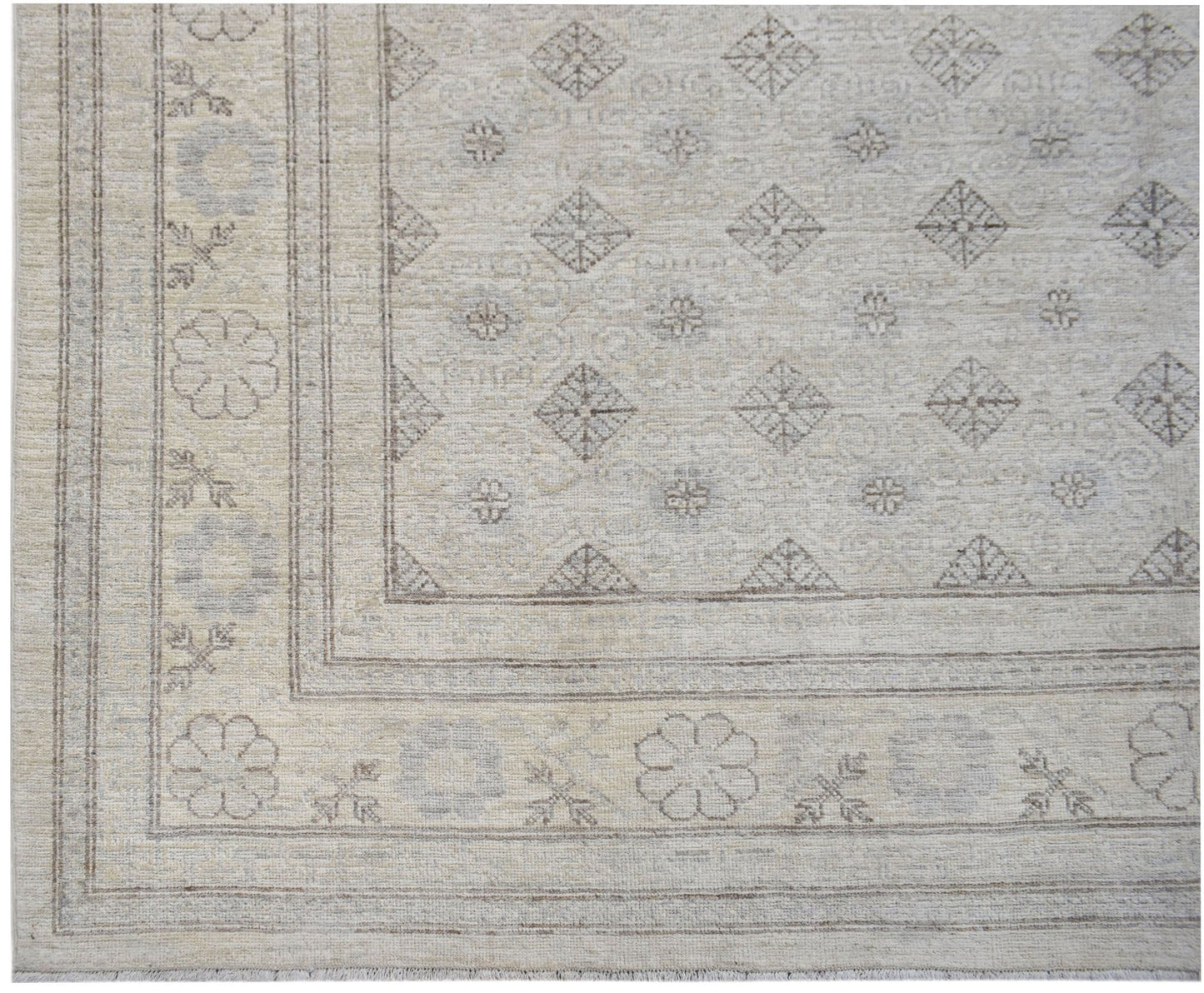 A handwoven Afghan Chobi rug featuring a neutral palette with geometric diamond and floral motifs.