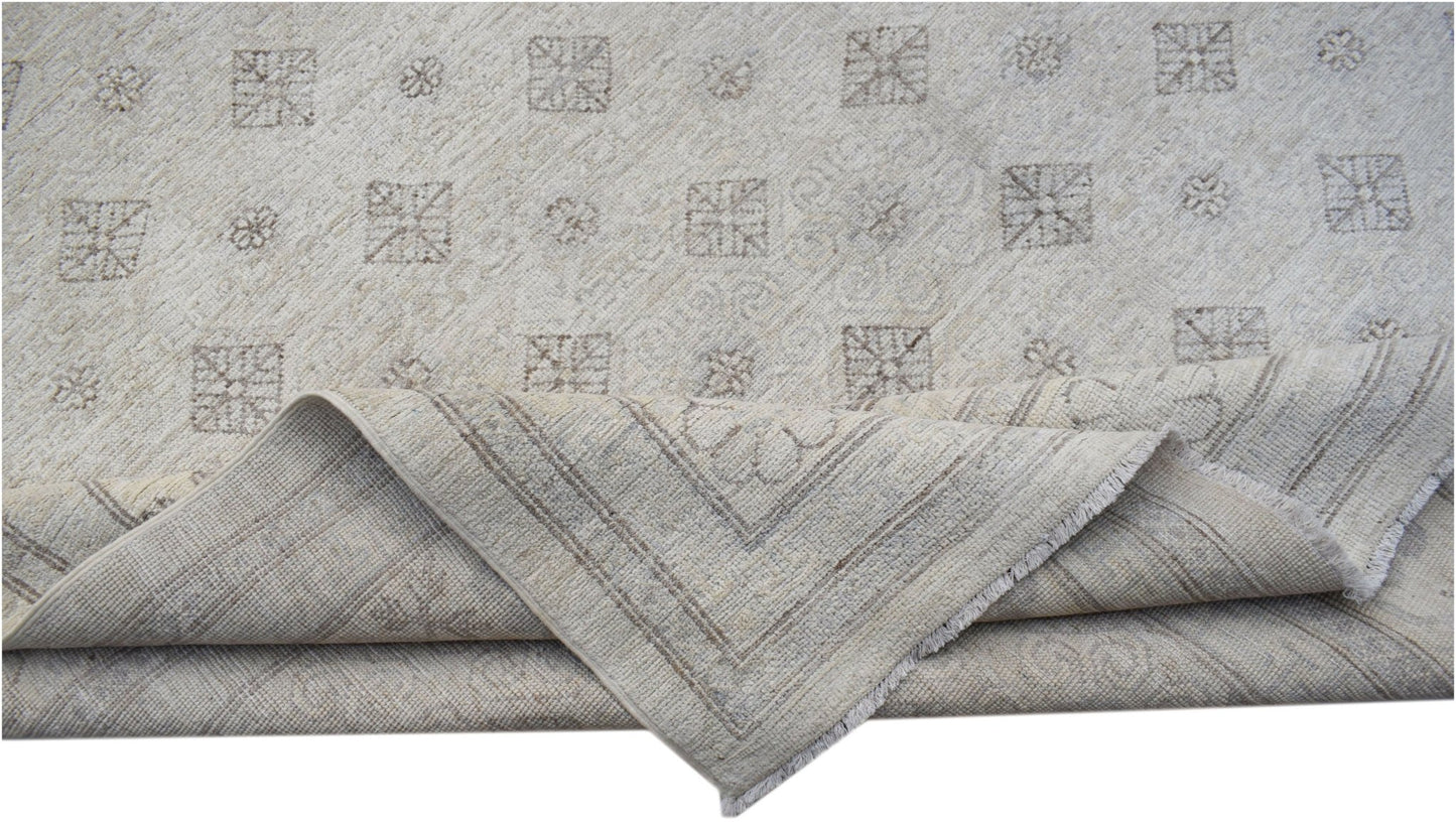 A handmade Afghan Chobi rug featuring a light beige field with geometric patterns and a folded corner.