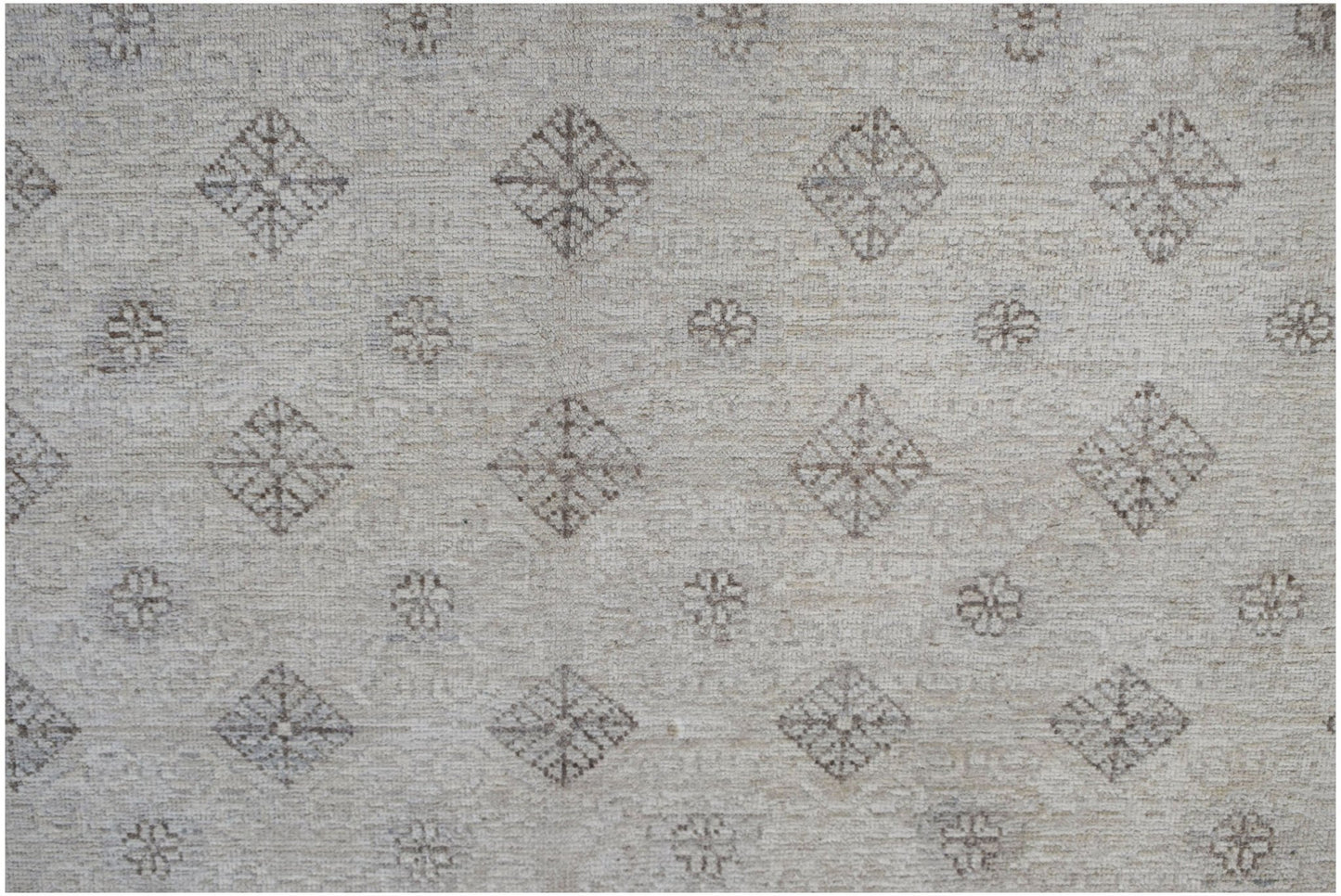 An Afghan Chobi rug featuring a repeating pattern of diamonds and floral motifs in neutral tones.