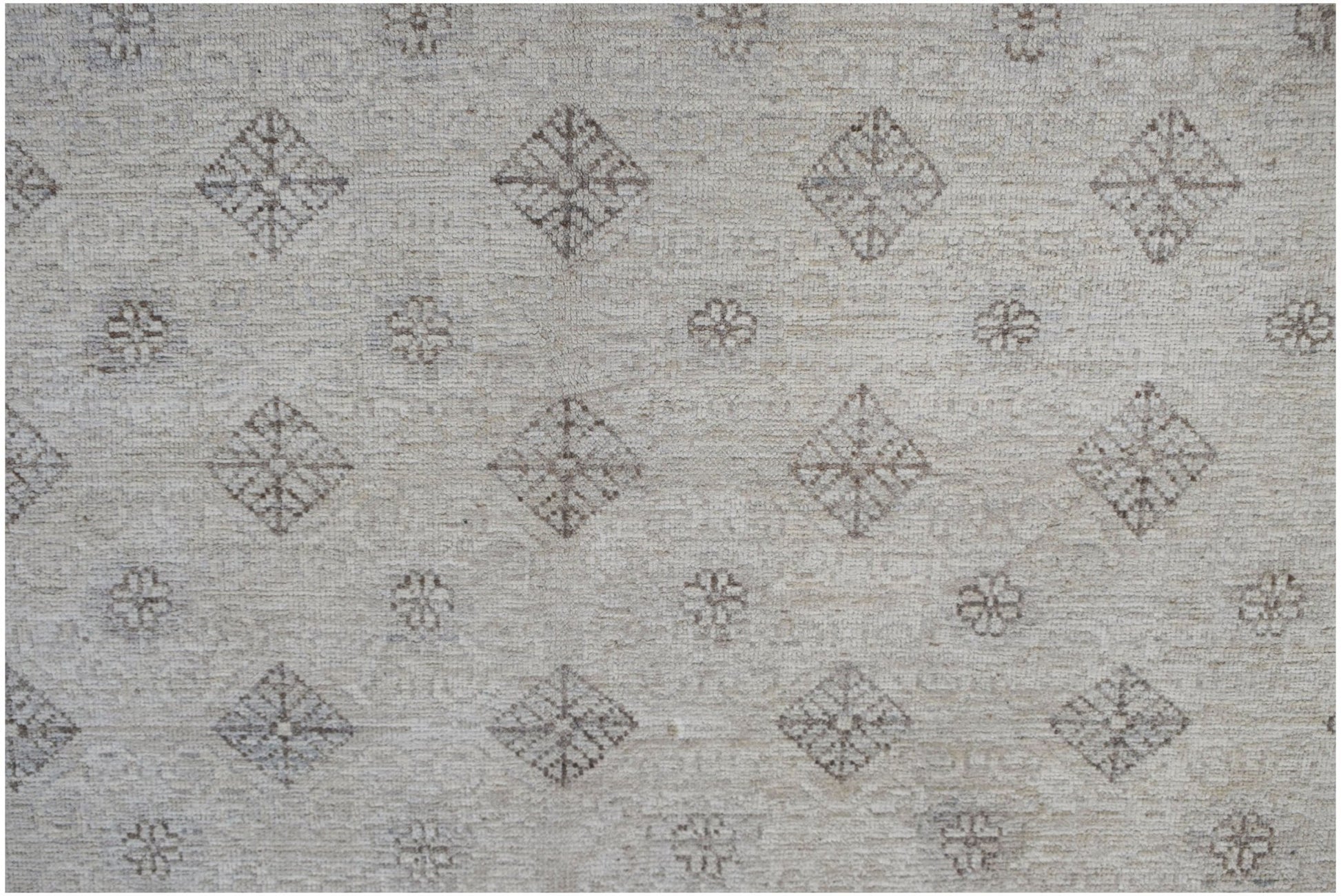 An Afghan Chobi rug featuring a repeating pattern of diamonds and floral motifs in neutral tones.