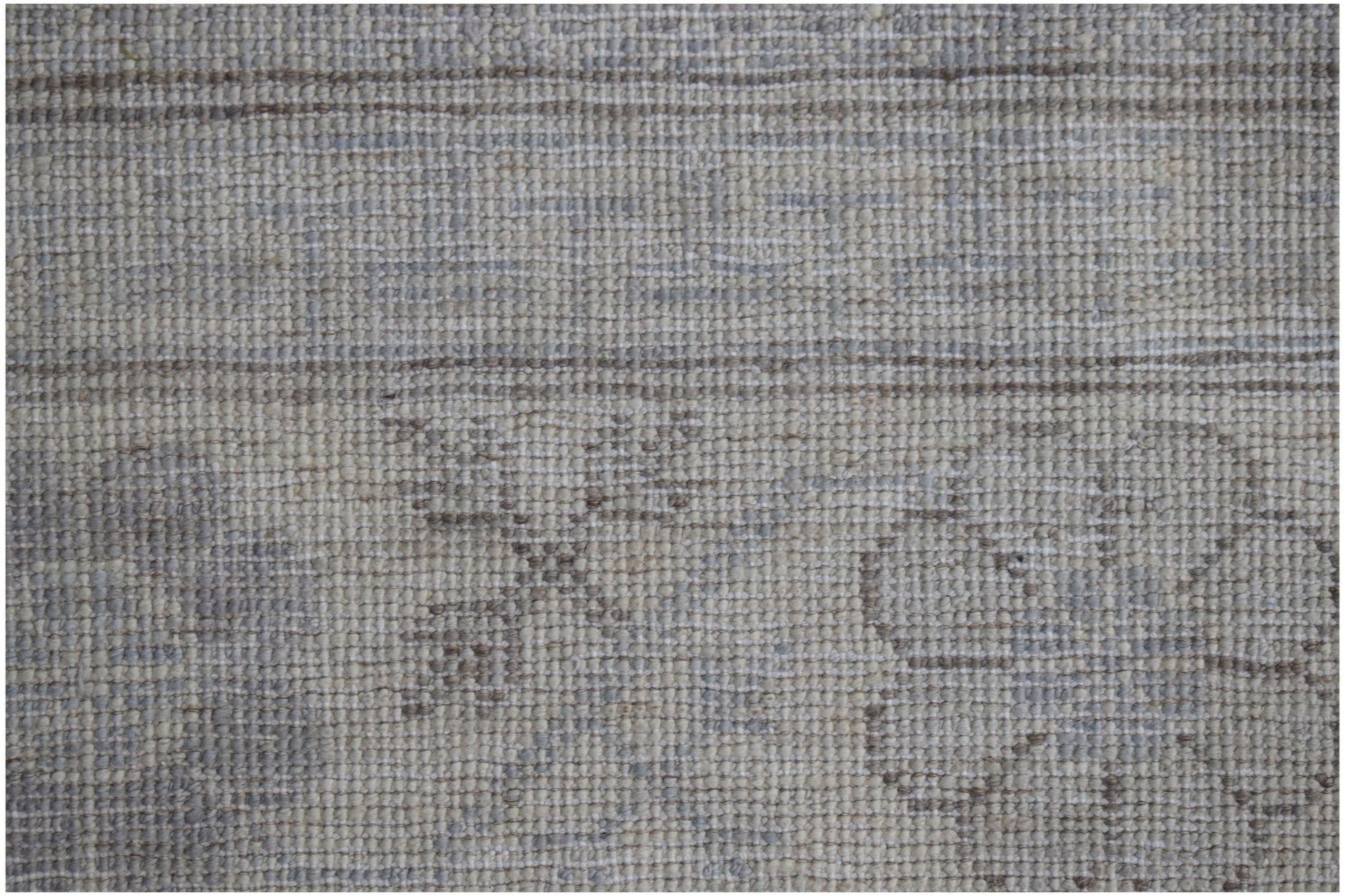 A close-up of a handwoven Afghan Chobi rug featuring a subtle, neutral-toned floral pattern.
