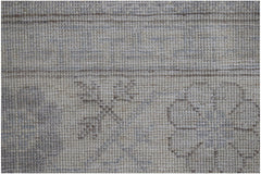 A close-up of a handwoven Afghan Chobi rug featuring a subtle, neutral-toned floral pattern.
