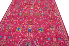 A handmade Afghan Chobi rug featuring a vibrant pink field with intricate floral patterns.
