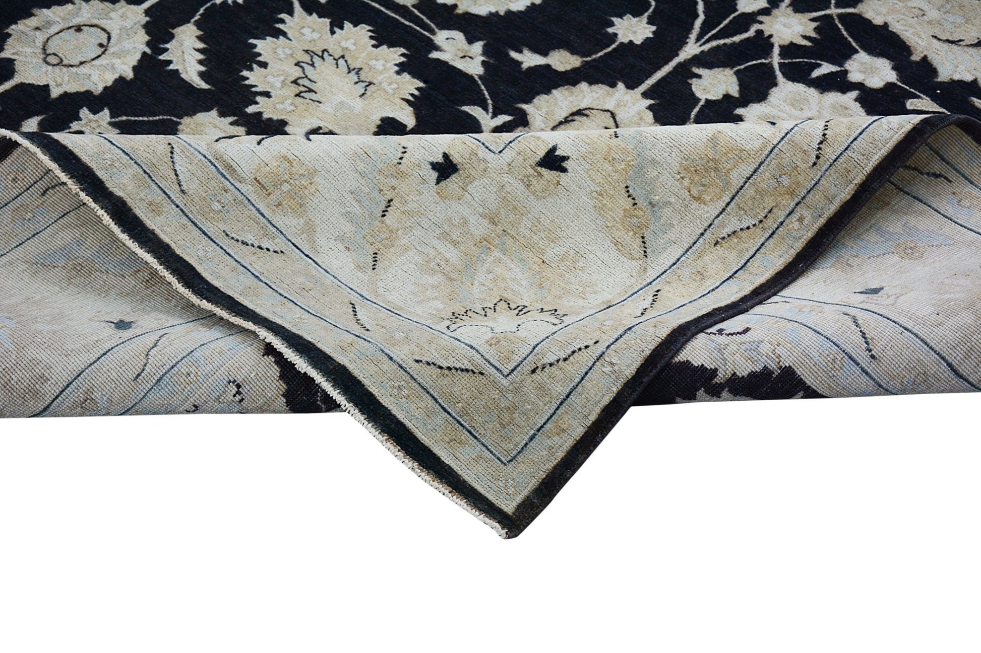A handmade Afghan Chobi rug with a black floral pattern folded to show its light underside.
