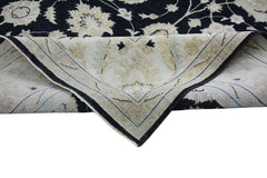 A handmade Afghan Chobi rug with a black floral pattern folded to show its light underside.