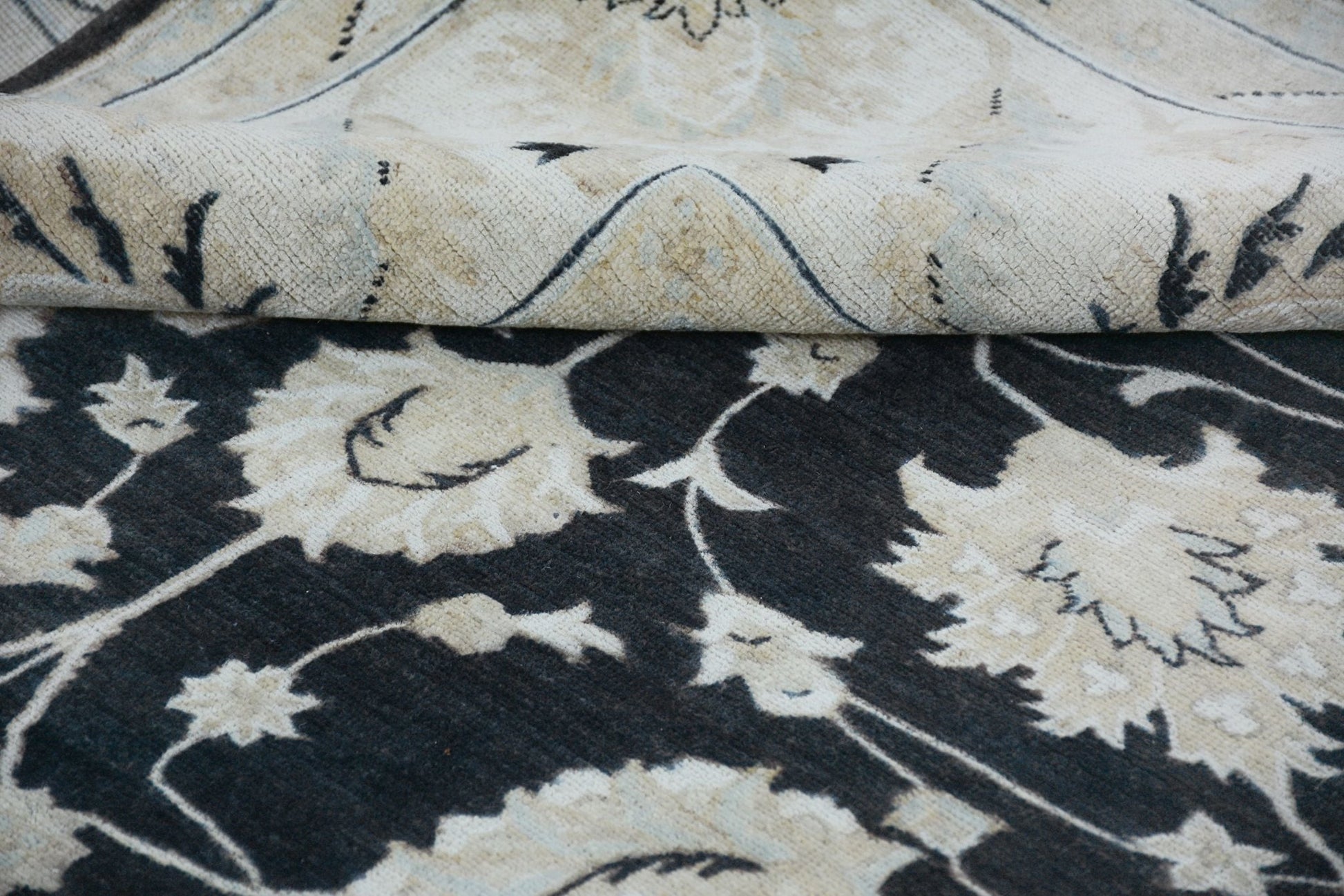 A handmade Afghan Chobi rug featuring a dark floral pattern with a folded corner showing the back.
