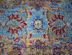 Handwoven Afghan Chobi rug featuring a traditional floral pattern in blue, gold, and red tones.