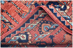 A corner of a handmade Afghan Chobi rug featuring traditional geometric patterns in red and blue.
