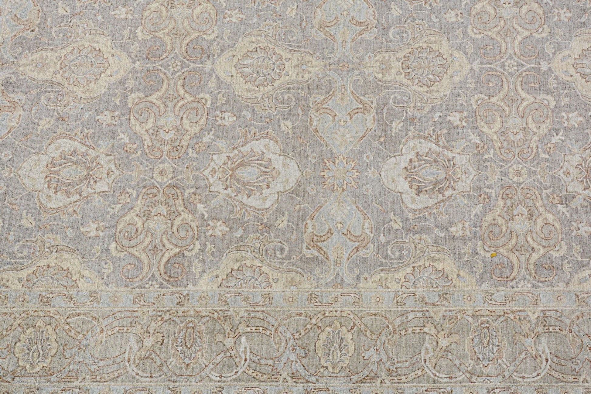 A handmade Afghan Chobi rug featuring a traditional floral pattern in soft beige and grey tones.