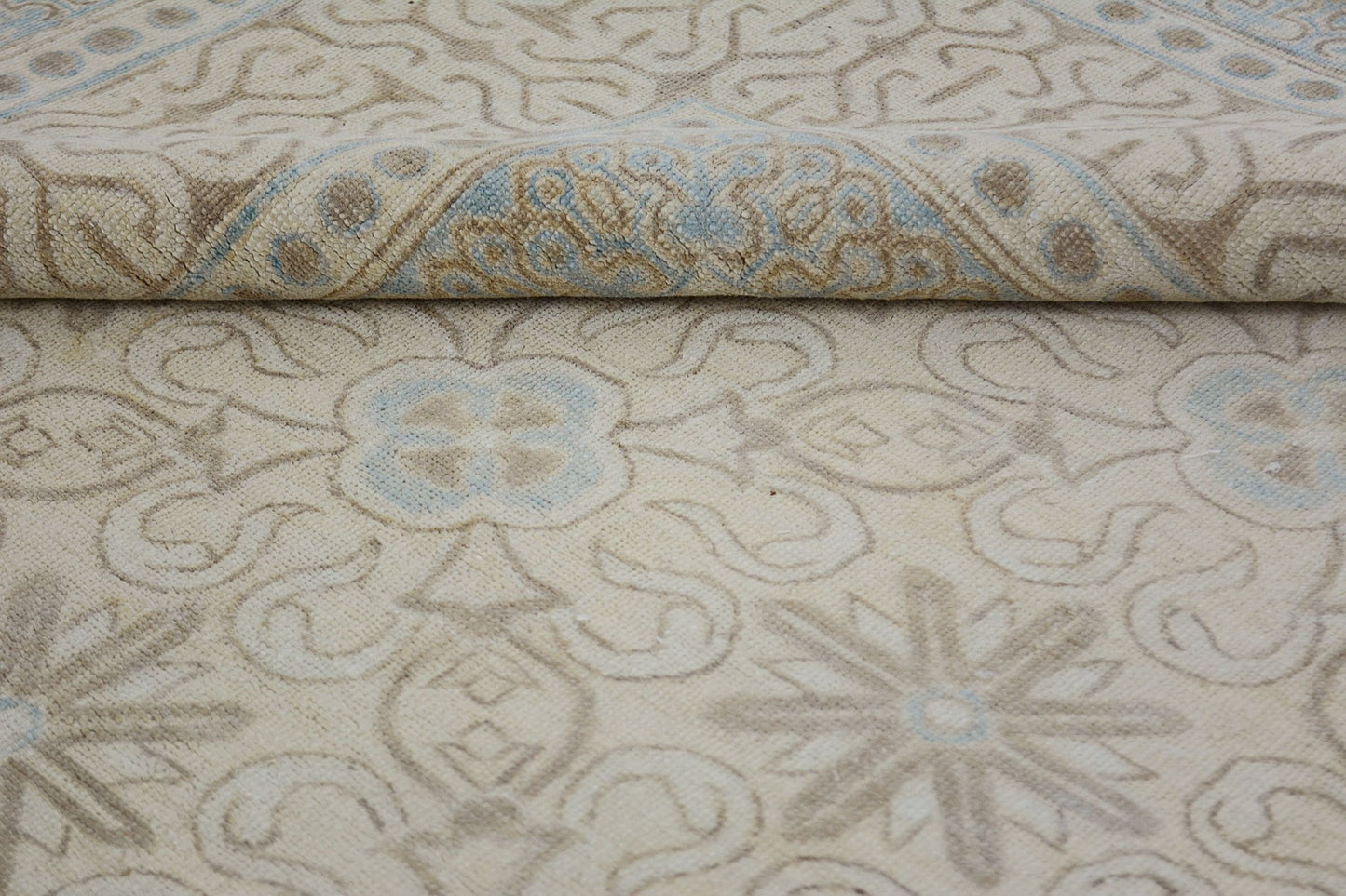 A handmade Afghan Chobi rug featuring a light beige field with soft blue and tan floral patterns.
