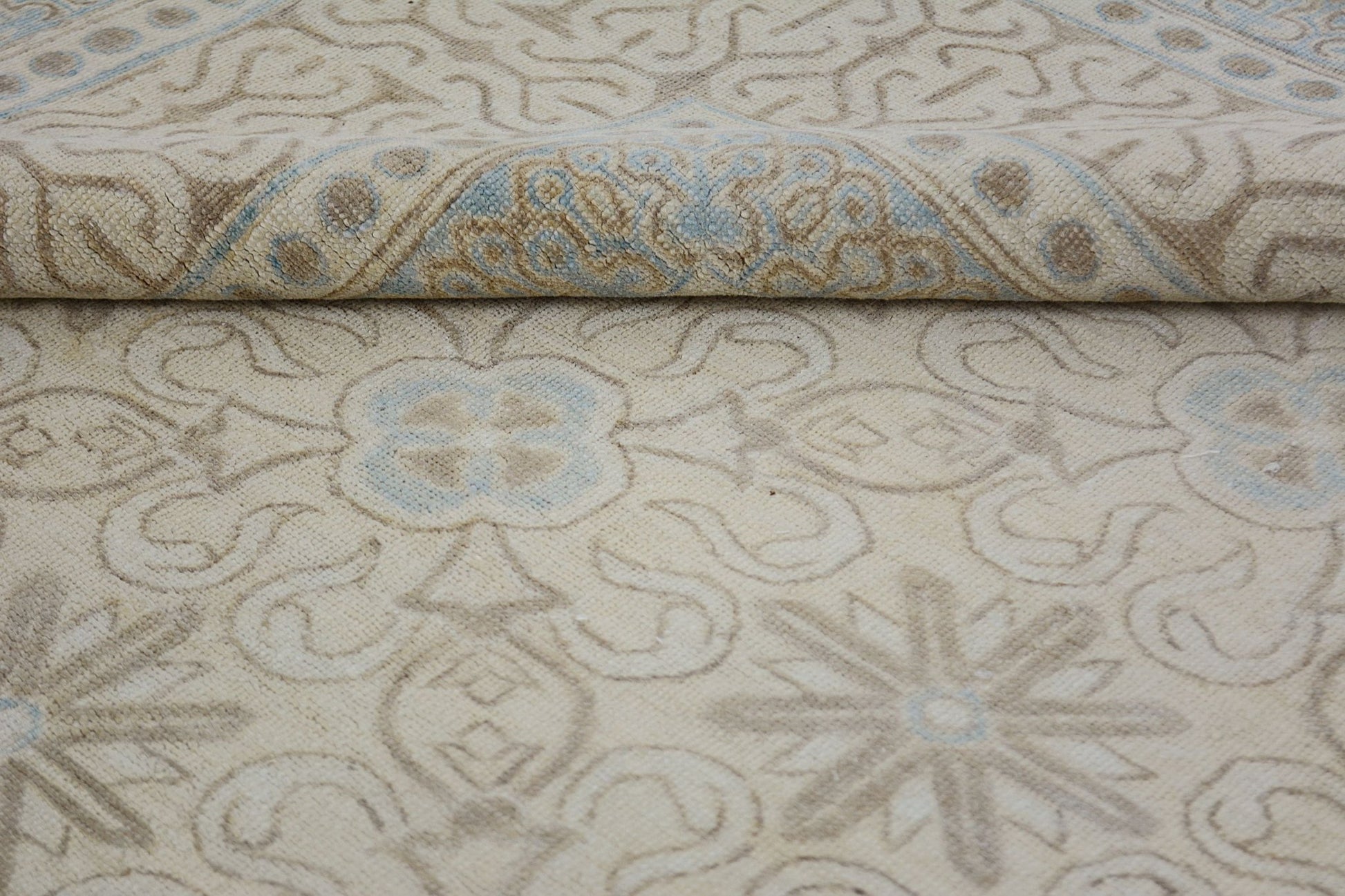 A handmade Afghan Chobi rug featuring a light beige field with soft blue and tan floral patterns.