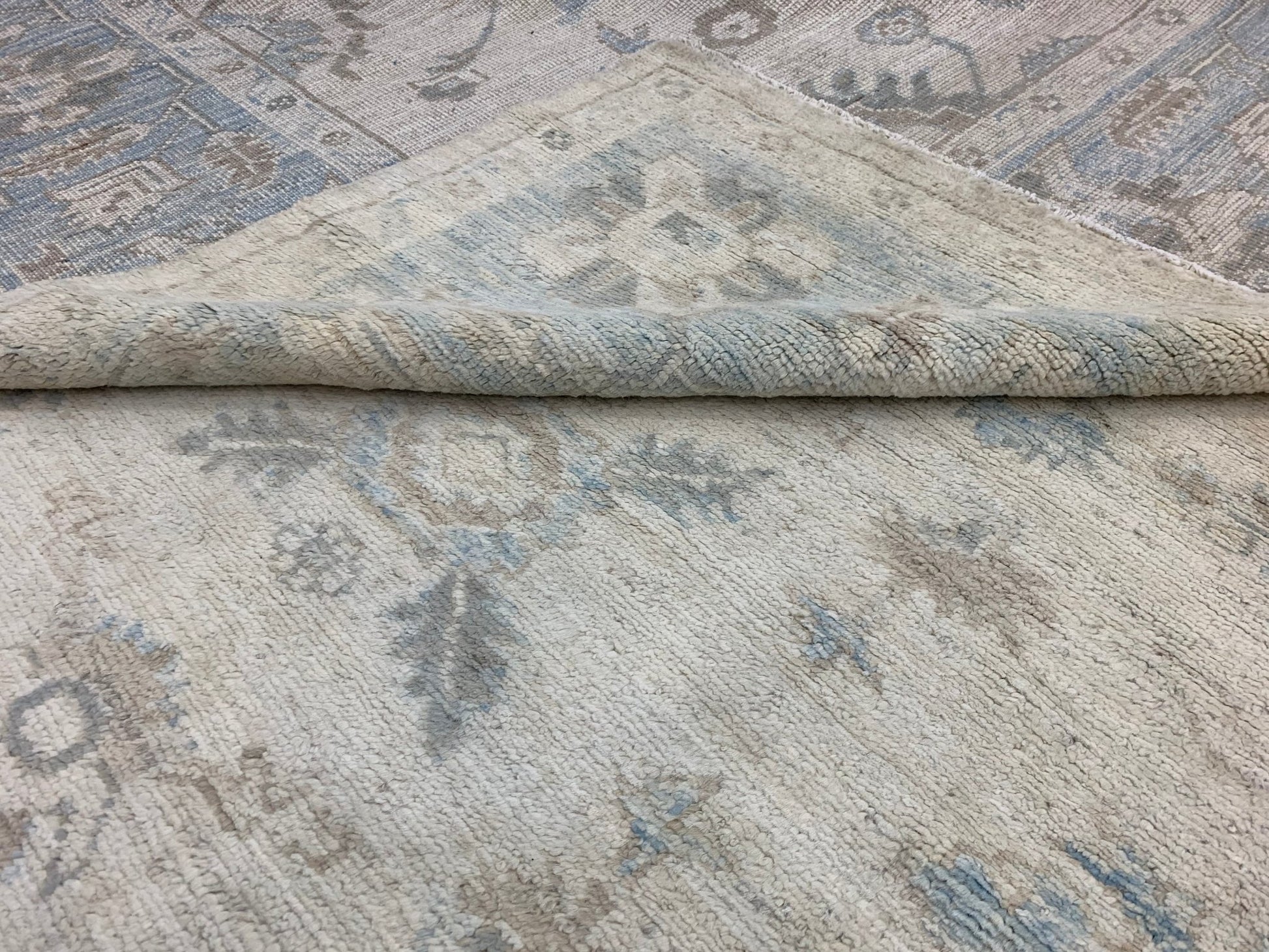 A handmade Afghan Chobi rug featuring a traditional floral pattern in soft blue and beige tones.
