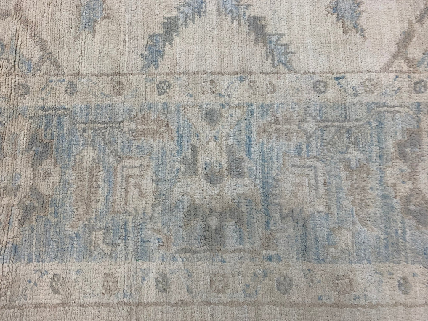 A handmade Afghan Chobi rug featuring a traditional geometric pattern in soft blue and beige tones.