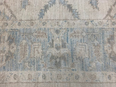 A handmade Afghan Chobi rug featuring a traditional geometric pattern in soft blue and beige tones.