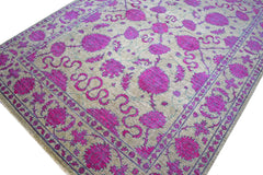 An Afghan Chobi rug featuring a vibrant magenta floral pattern on a neutral beige background.