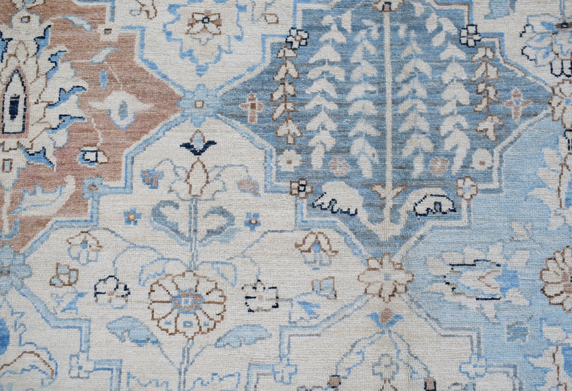 A handwoven Afghan Chobi rug featuring a traditional floral pattern in shades of blue and tan.