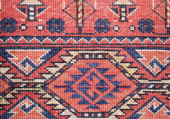 A close-up of a handmade Afghan Chobi rug featuring traditional geometric patterns in red and blue.