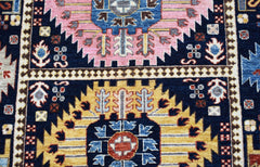 A handwoven Afghan Chobi rug featuring geometric floral medallions in pink, yellow, and blue.
