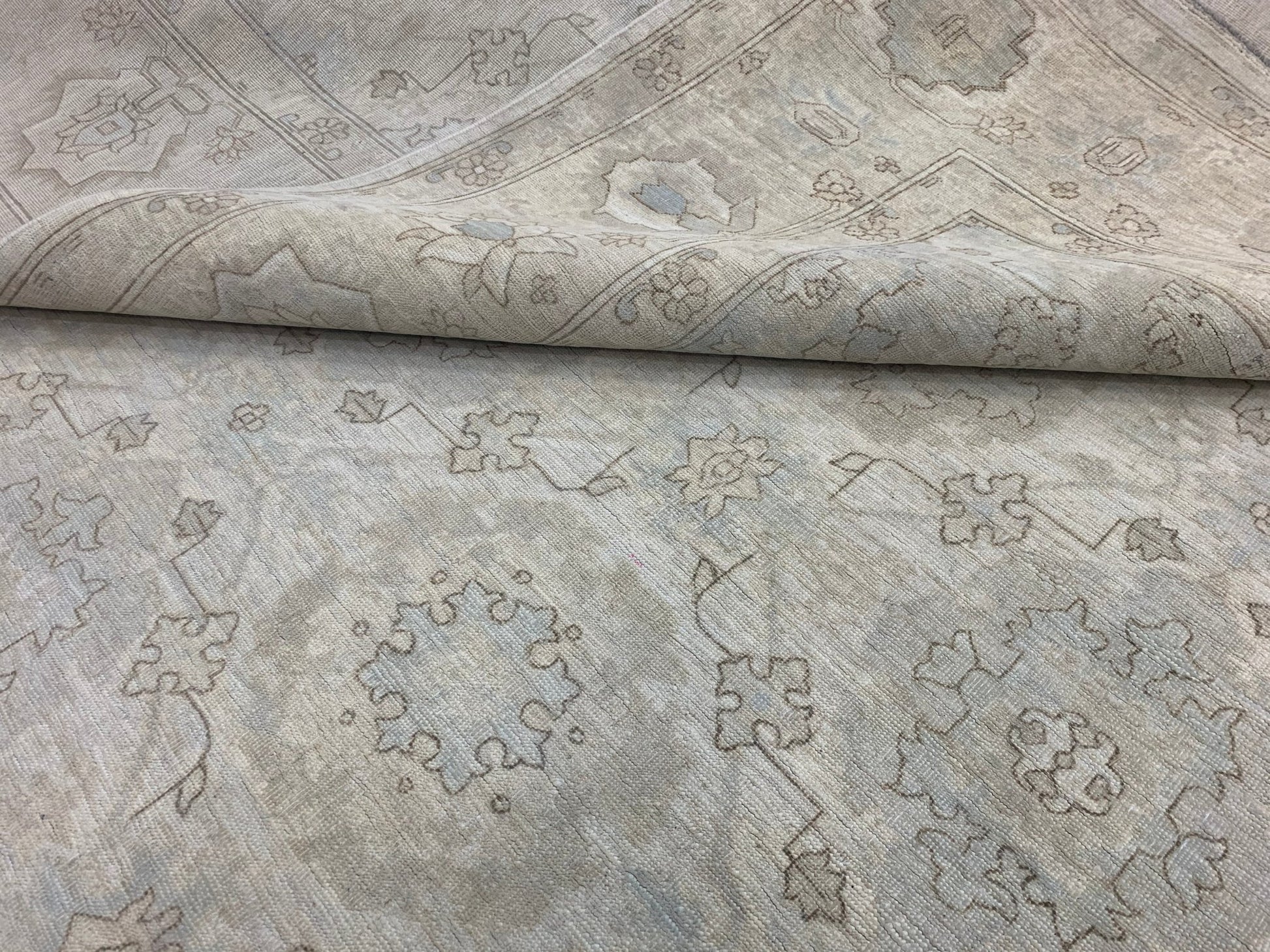 A handmade Afghan Chobi rug featuring a neutral, wood-toned floral pattern on a wool pile.
