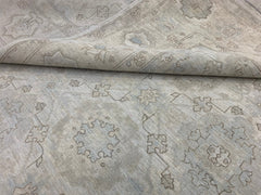 A handmade Afghan Chobi rug featuring a neutral, wood-toned floral pattern on a wool pile.