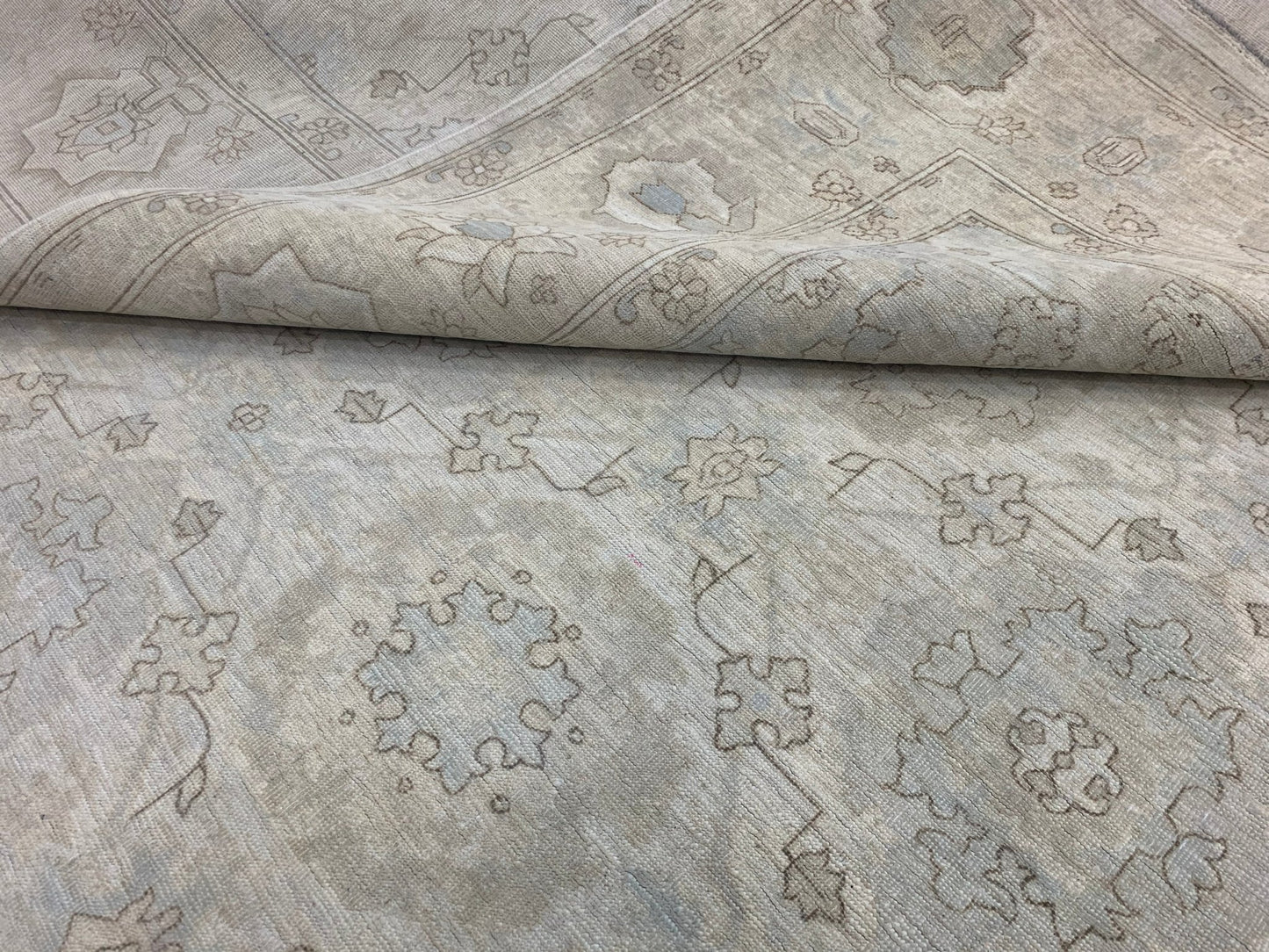A handmade Afghan Chobi rug featuring a neutral, wood-toned floral pattern on a wool pile.