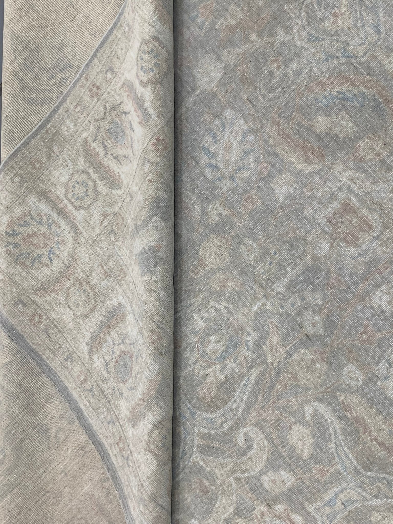 A handmade Afghan Chobi rug featuring a traditional floral pattern in muted grey and beige tones.