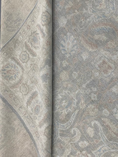 A handmade Afghan Chobi rug featuring a traditional floral pattern in muted grey and beige tones.