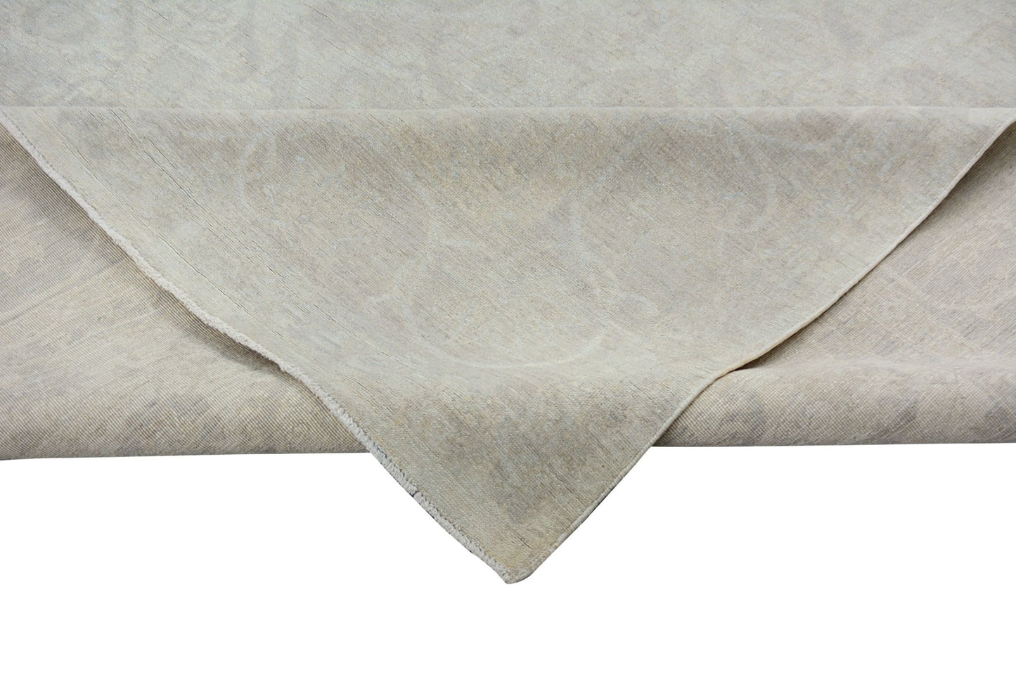 A corner of a handmade Afghan Chobi rug featuring a subtle, light-toned traditional pattern.