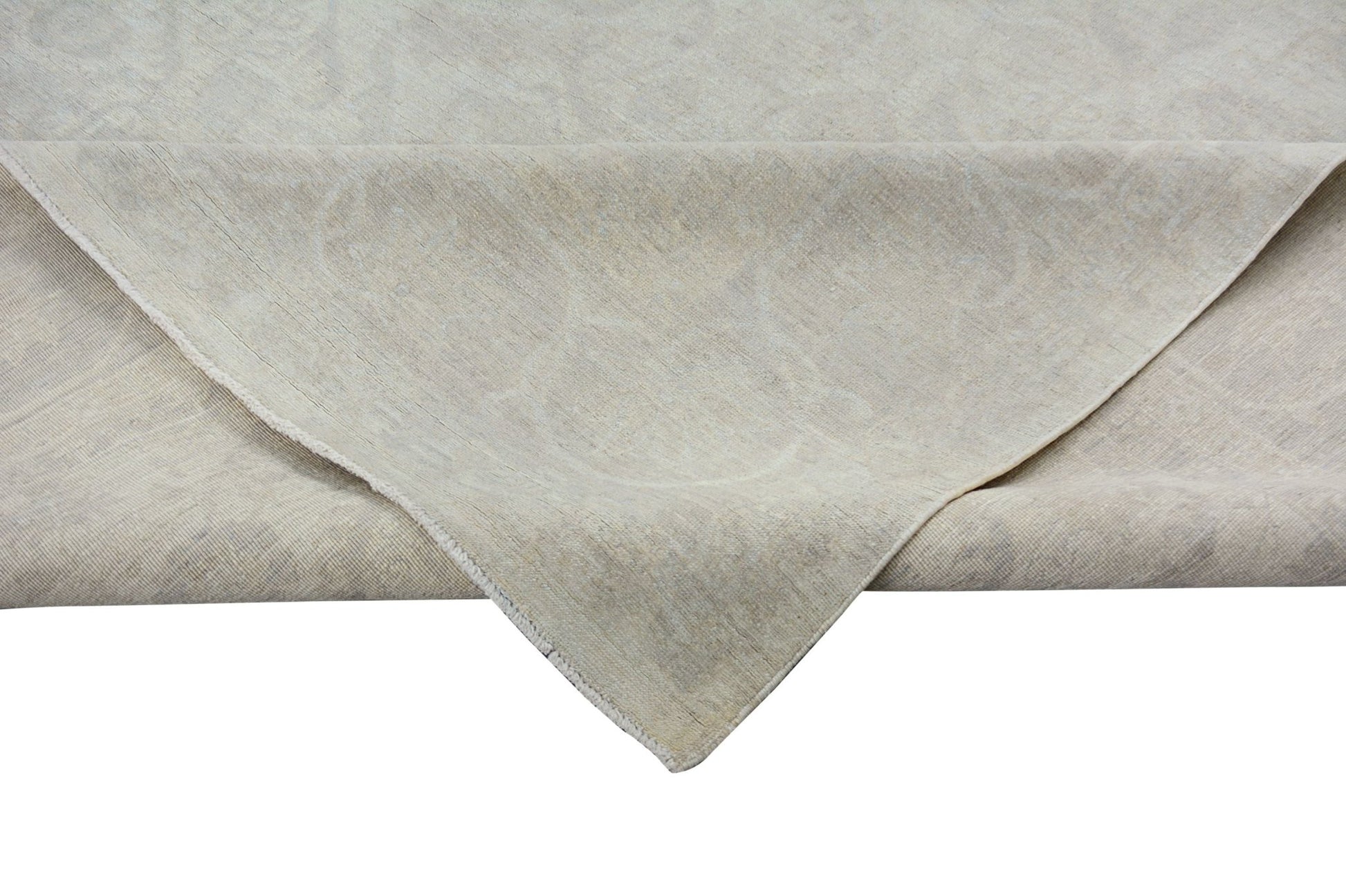 A corner of a handmade Afghan Chobi rug featuring a subtle, light-toned traditional pattern.