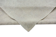 A corner of a handmade Afghan Chobi rug featuring a subtle, light-toned traditional pattern.
