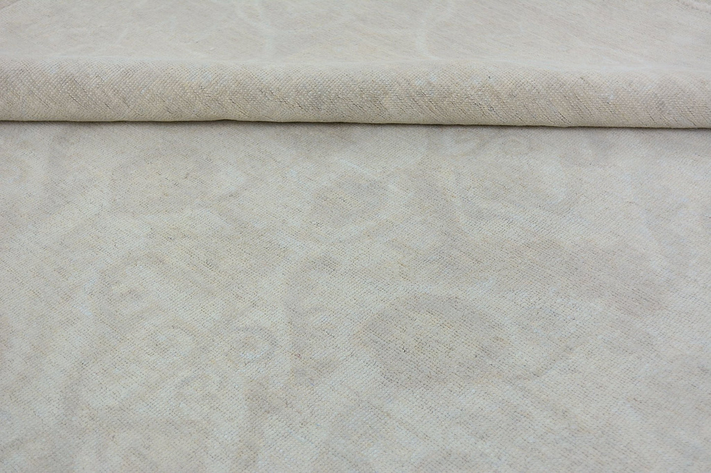 A handmade Afghan Chobi rug featuring a subtle, monochromatic cream-colored floral pattern.