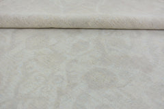 A handmade Afghan Chobi rug featuring a subtle, monochromatic cream-colored floral pattern.