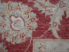 A close-up of a handwoven Afghan Chobi rug featuring intricate floral patterns in red and beige.