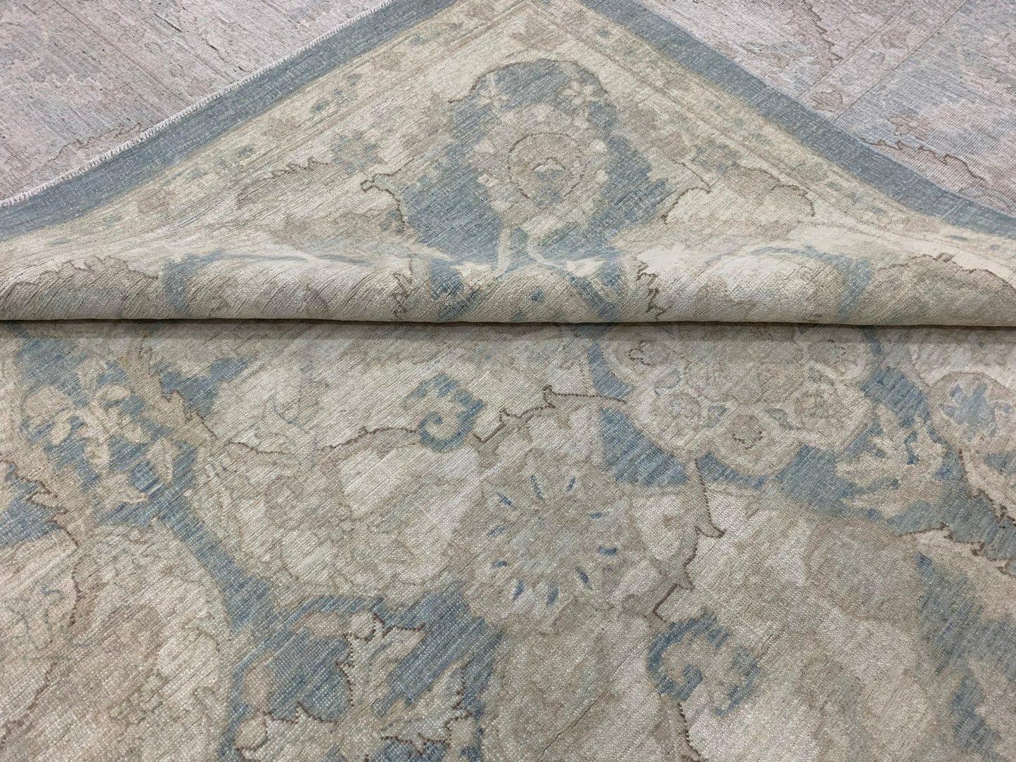 A handmade Afghan Chobi rug featuring a traditional floral pattern in soft blue and beige tones.