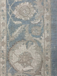A handmade Afghan Chobi rug featuring a traditional floral pattern in shades of blue and beige.