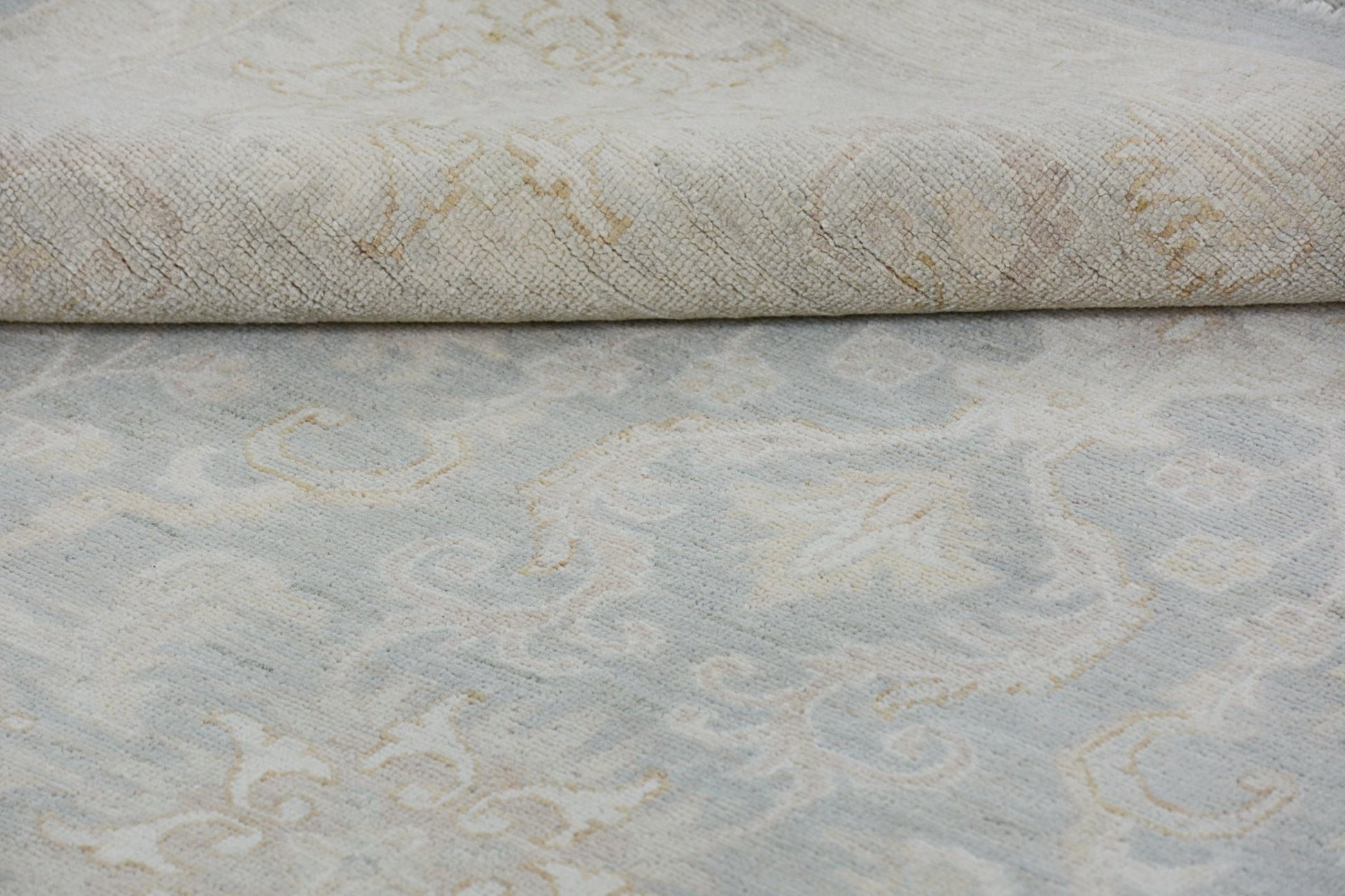 A handmade Afghan Chobi rug featuring a traditional floral pattern in soft blue and beige tones.