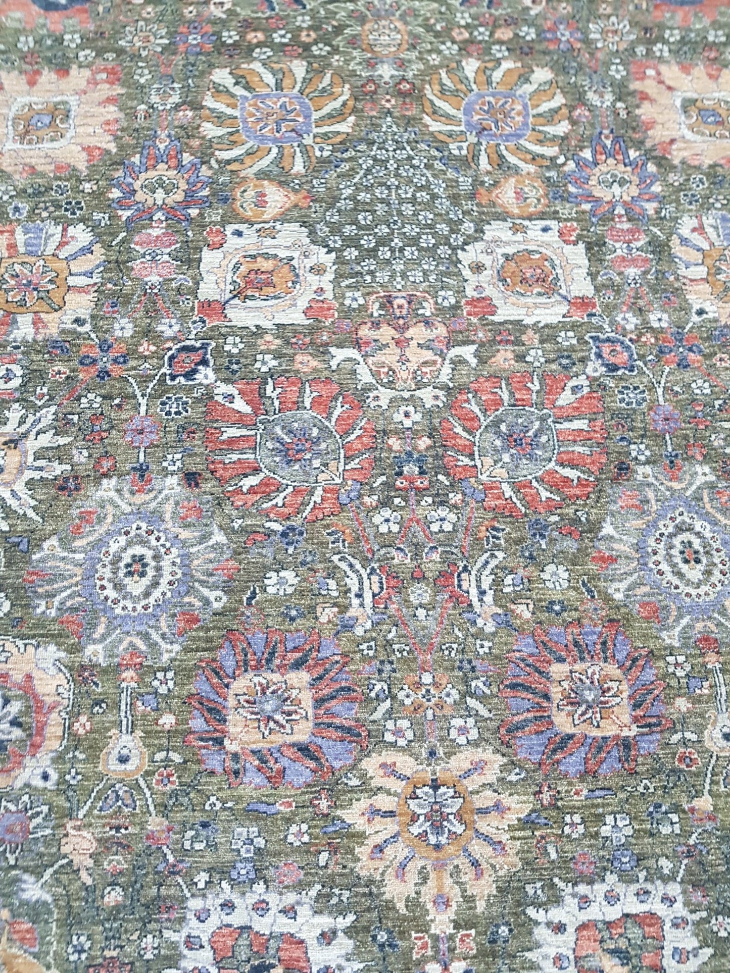 An Afghan Chobi rug featuring a traditional floral pattern in muted earth tones on a green field.