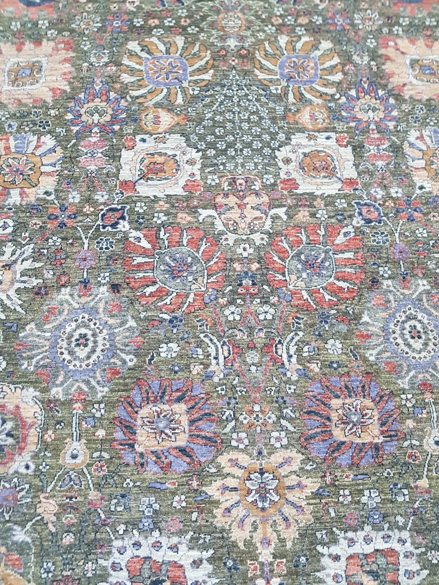 An Afghan Chobi rug featuring a traditional floral pattern in muted earth tones on a green field.