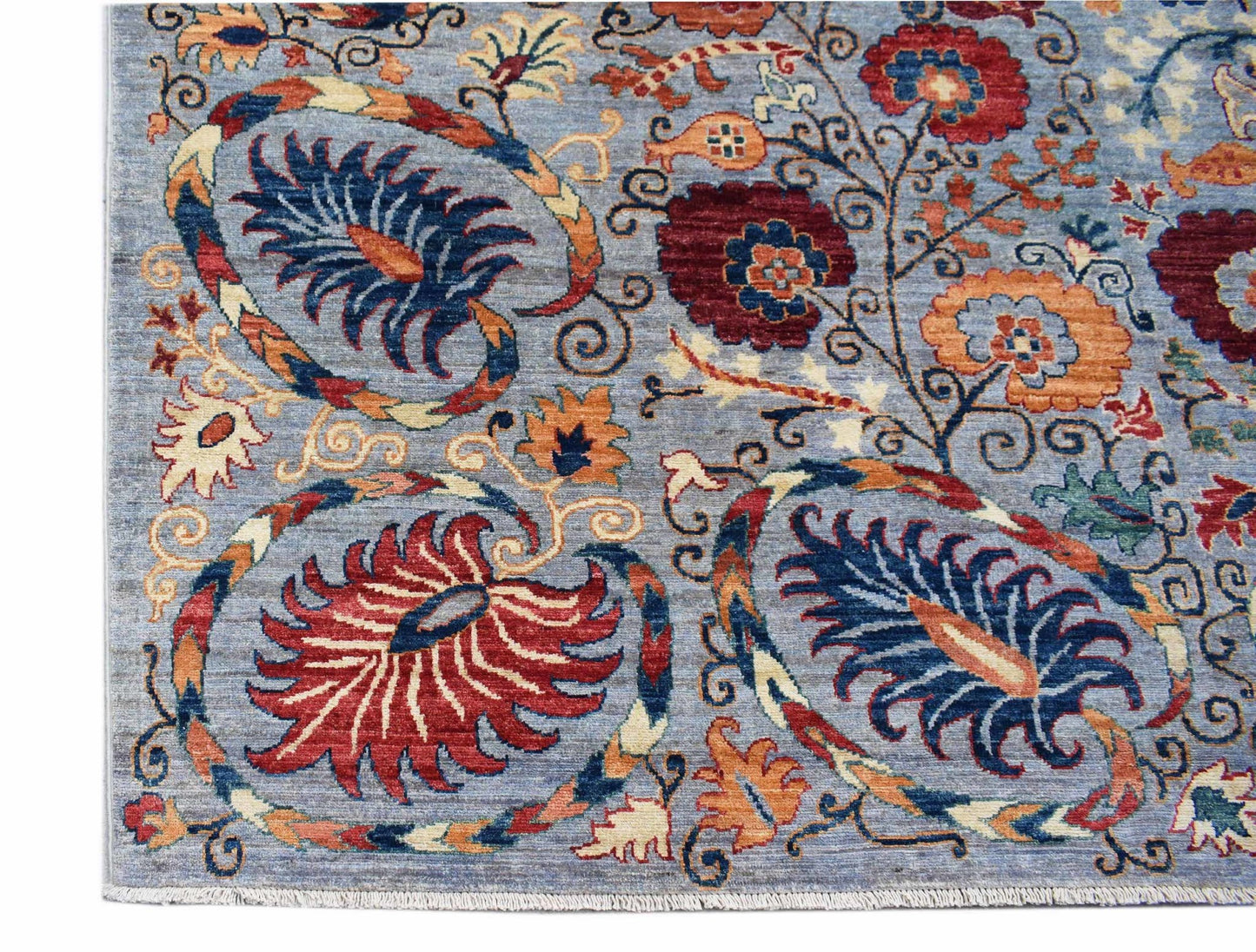 An Afghan Chobi rug featuring intricate floral patterns in red, blue, and orange on a blue field.