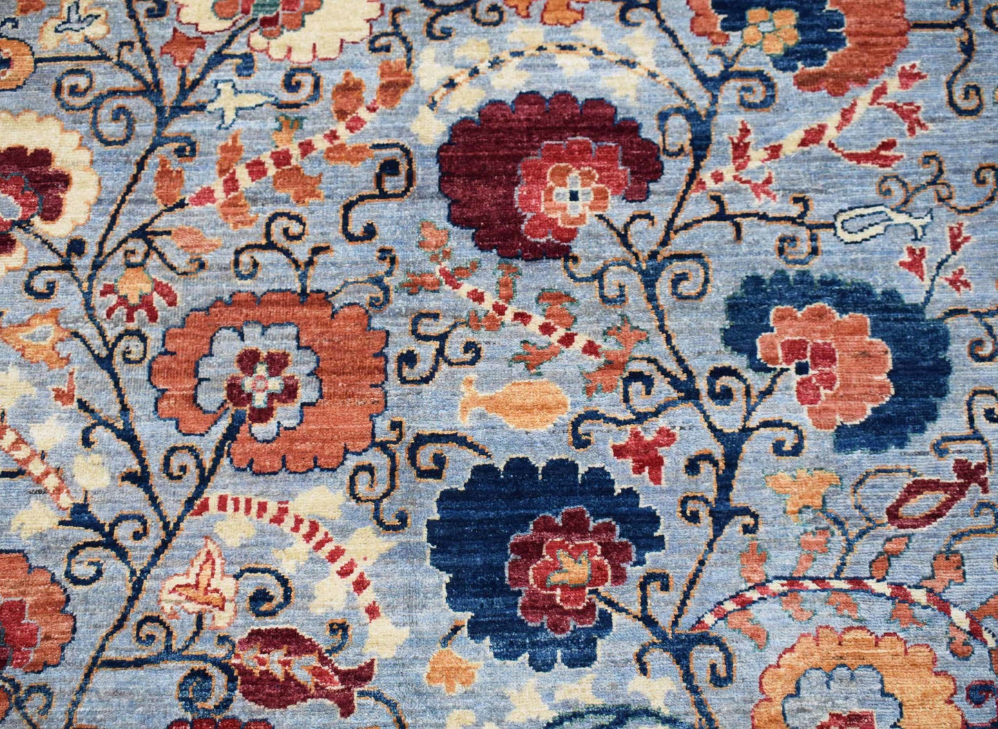 Handwoven Afghan Chobi rug featuring a floral pattern in shades of blue, red, and cream.