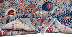 A handwoven Afghan Chobi rug featuring a floral pattern in blue, red, and earthy tones.