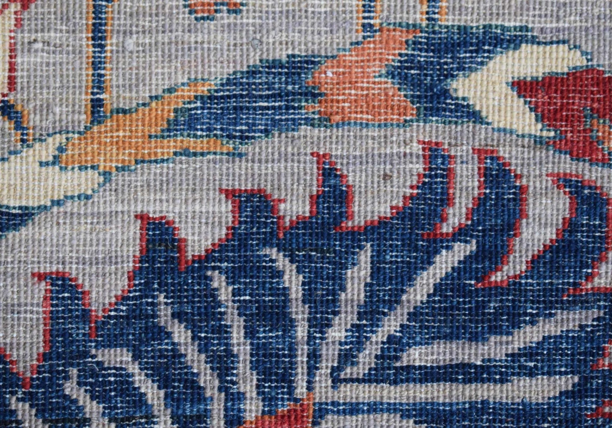 A close-up view of a handwoven Afghan Chobi rug featuring intricate blue and red floral patterns.