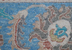 A close-up view of a handwoven Afghan Chobi rug featuring intricate floral patterns in blue and tan.
