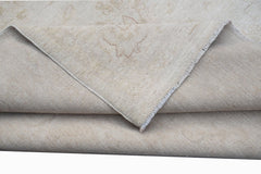 A handwoven Afghan Chobi rug in neutral beige tones with a folded corner showing the cotton base.