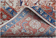 A folded Afghan Chobi rug featuring a traditional floral pattern in red, blue, and beige tones.