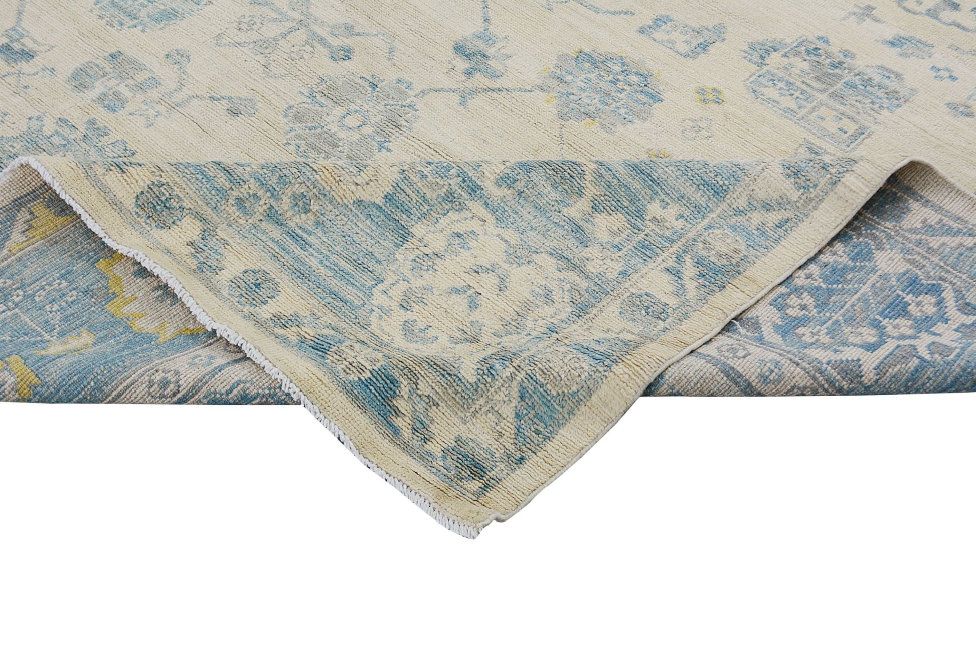 A handmade Afghan Chobi rug with a cream background and blue floral patterns, shown folded.
