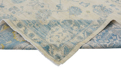 A handmade Afghan Chobi rug with a cream background and blue floral patterns, shown folded.
