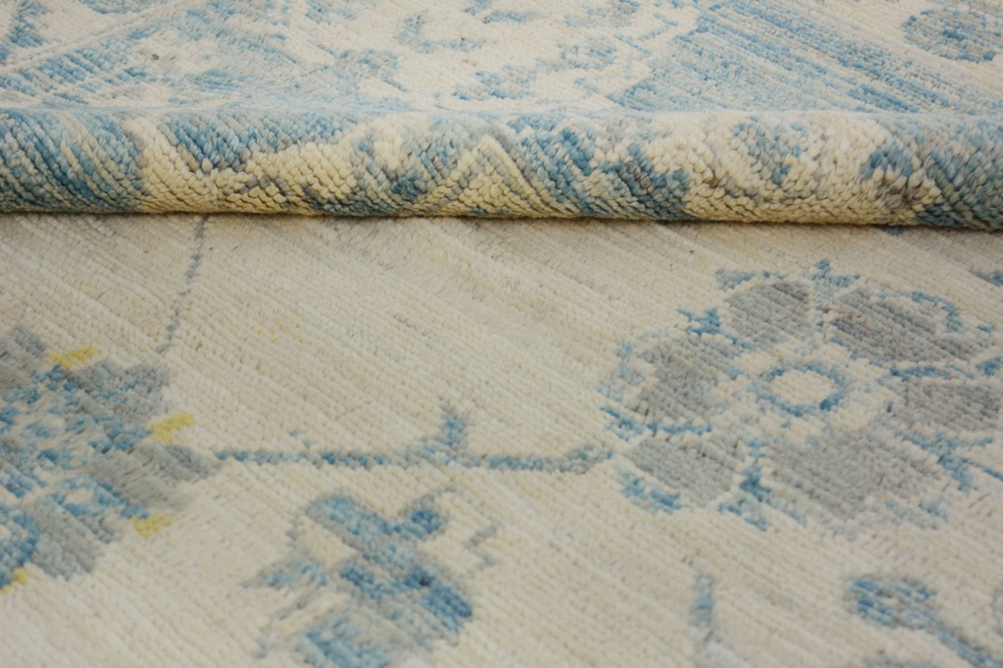 A handmade Afghan Chobi rug featuring a traditional floral pattern in blue and cream tones.
