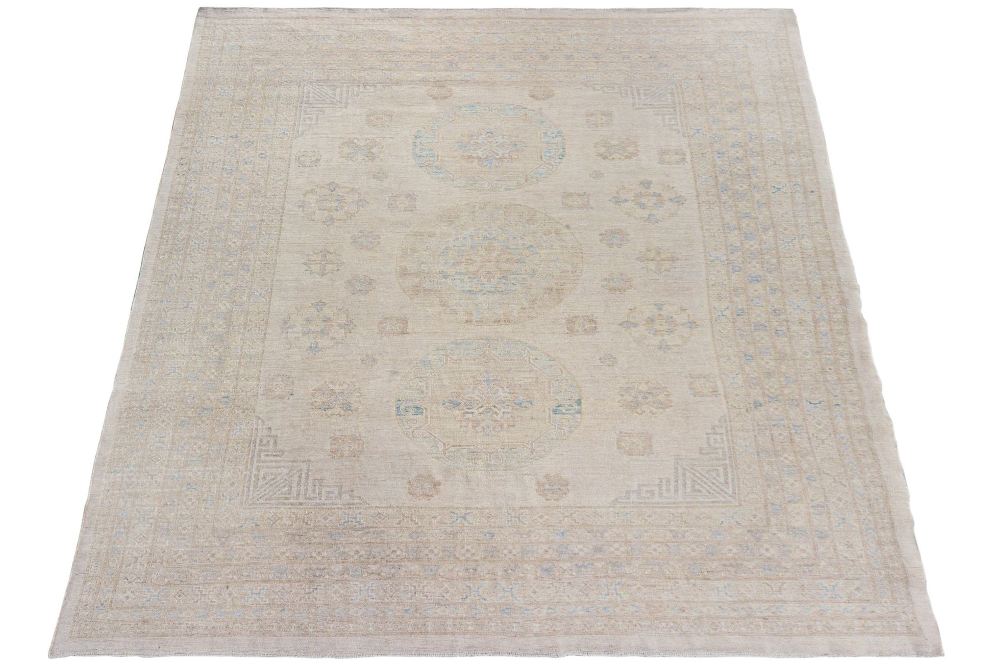 A handmade Afghan Chobi rug featuring a neutral beige palette with subtle blue medallion patterns.